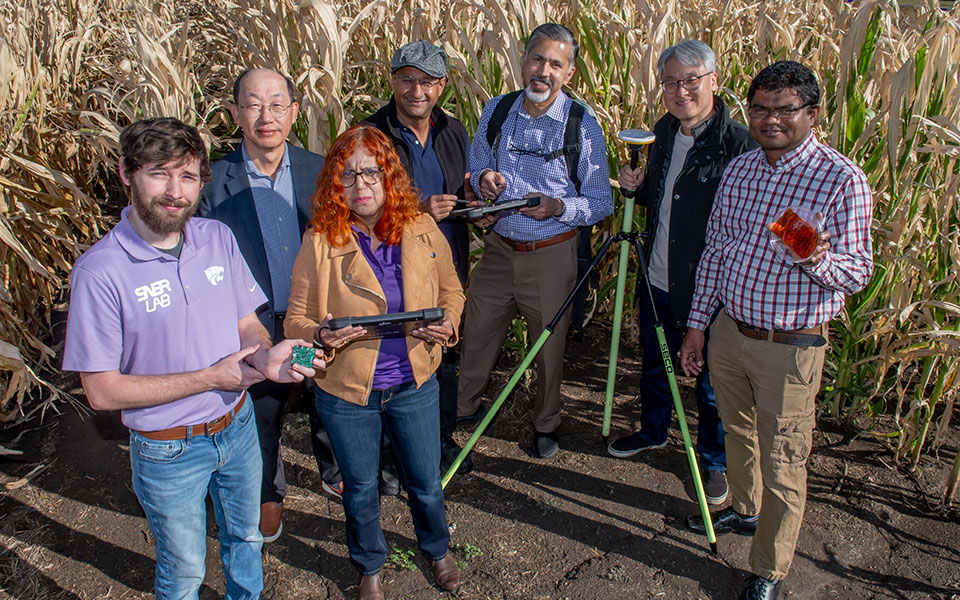 Seven people standing in front of corn field