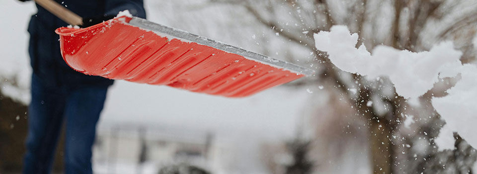 Closeup, snow being thrown from orange shovel