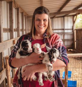 Telia Keys holding three milking goats