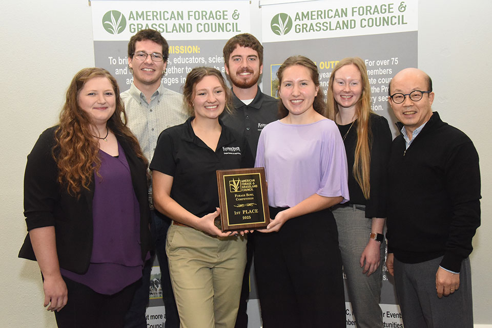 group photo of k-state forage bowl team with national champions trophy