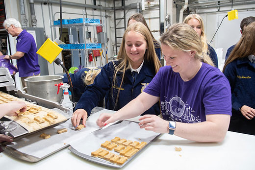 Two girls placing dog biscuits on a cookie tray