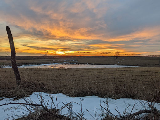 Kansas Scene, farm field with spots of snow at sunset