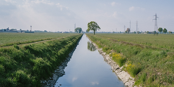 Long view of canal holding water, farm scene