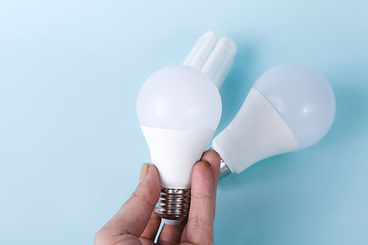 Blue Background with a hand holding two lightbulbs