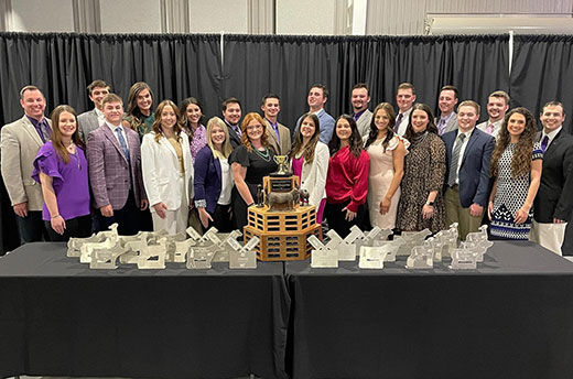 Group photo, K-State meat animal evaluation team with numerous trophies set on table Group photo, K-State meat animal evaluation team with numerous trophies set on table