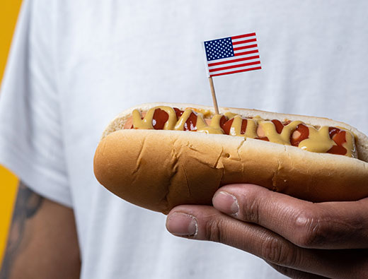 Closeup of man holding hot dog with American flag